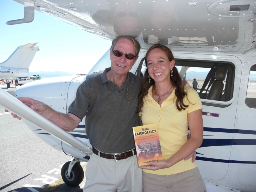 Flight instructor and student with the book they worked on together under the wing of a Cessna 172